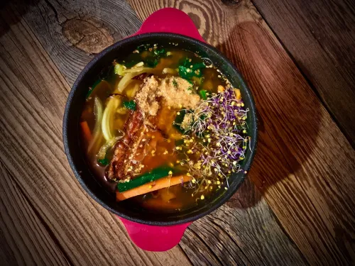 Wegański ramen vegestyl z warzywami i makaronem na drewnianym stole.